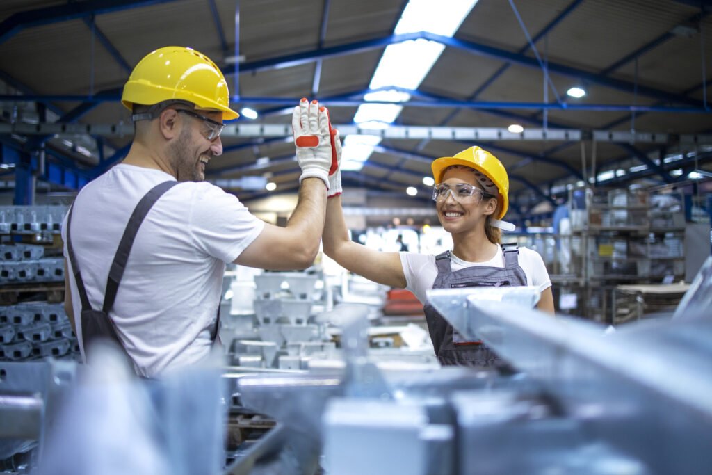 Factory workers greeting each other for successful teamwork.